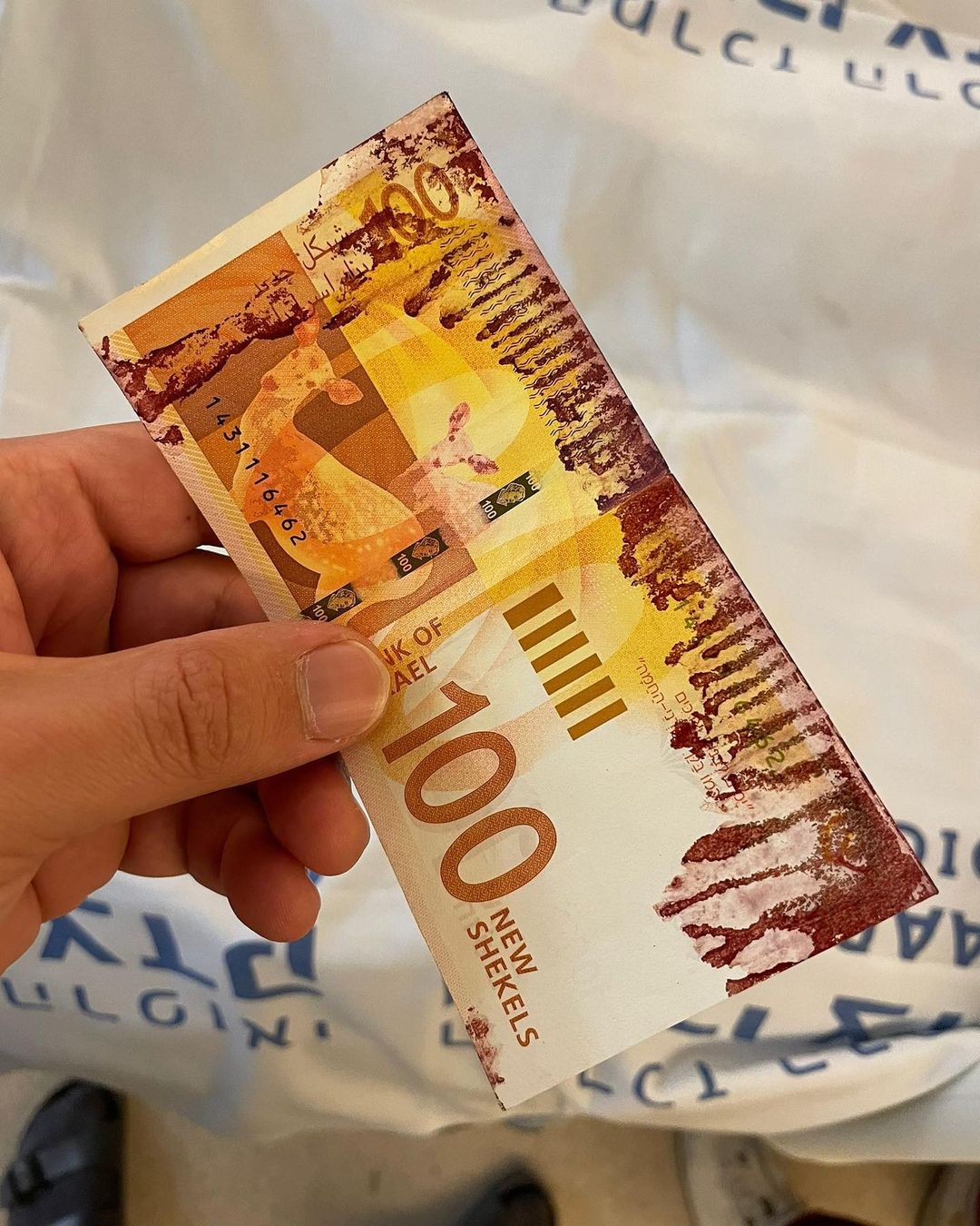 A hundred shekel bill stained with blood