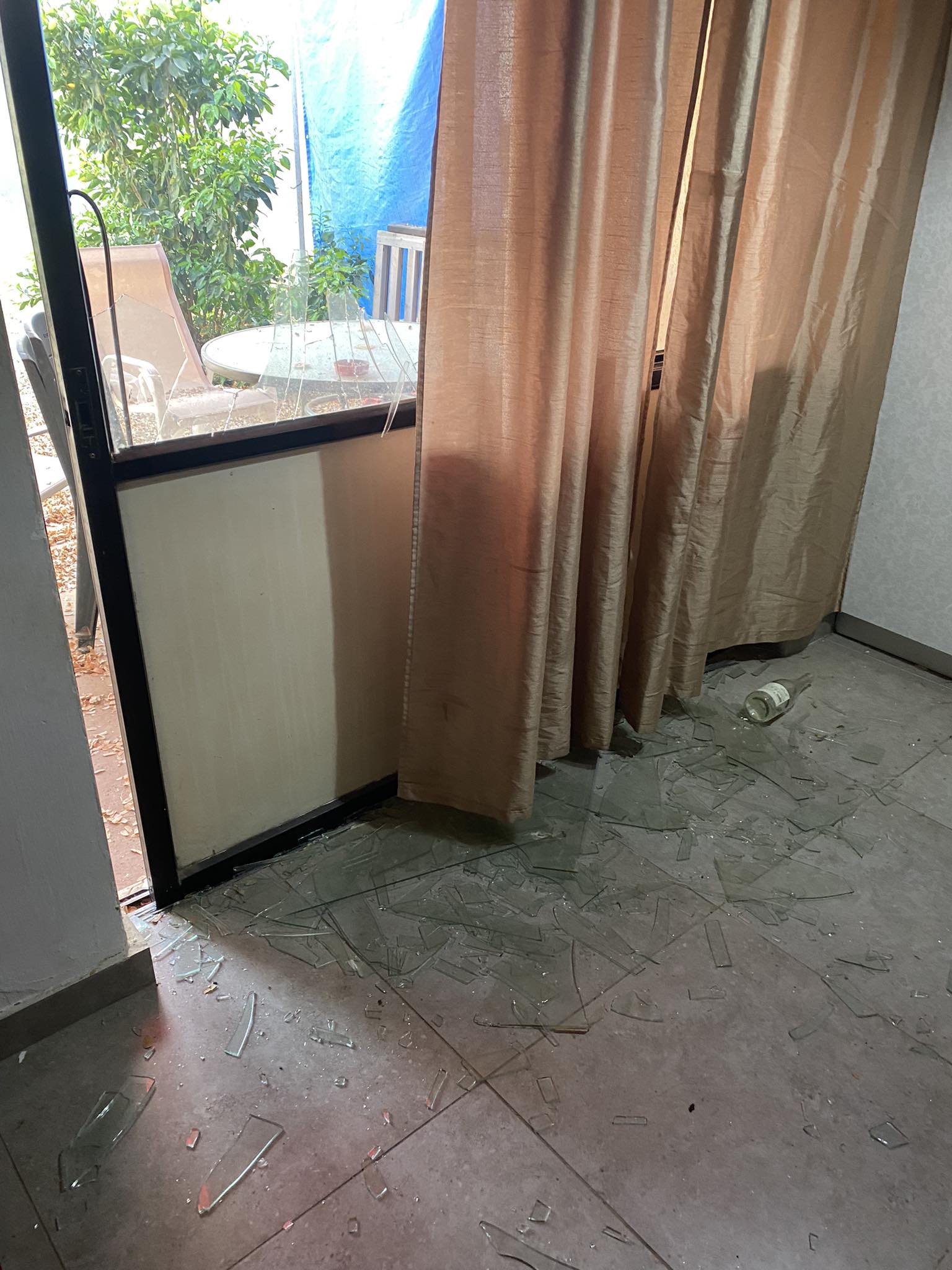 A broken window with a curtain pulled aside