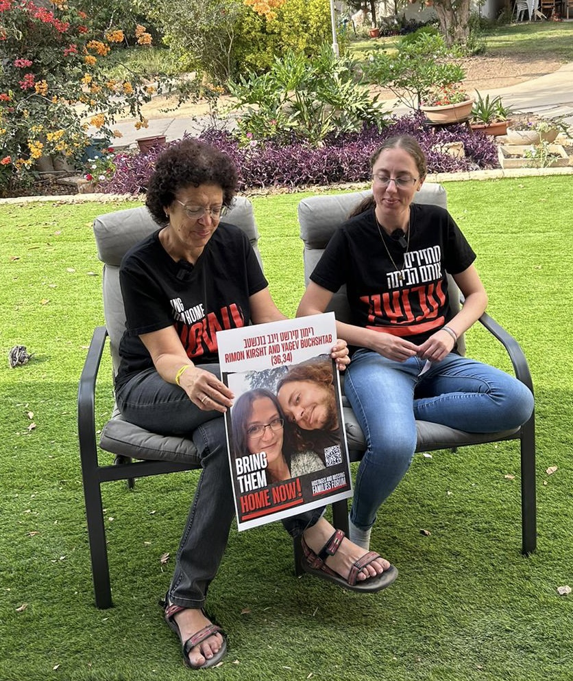 Esther B. sitting on the left holding a poster of kidnapped son and daughter in law