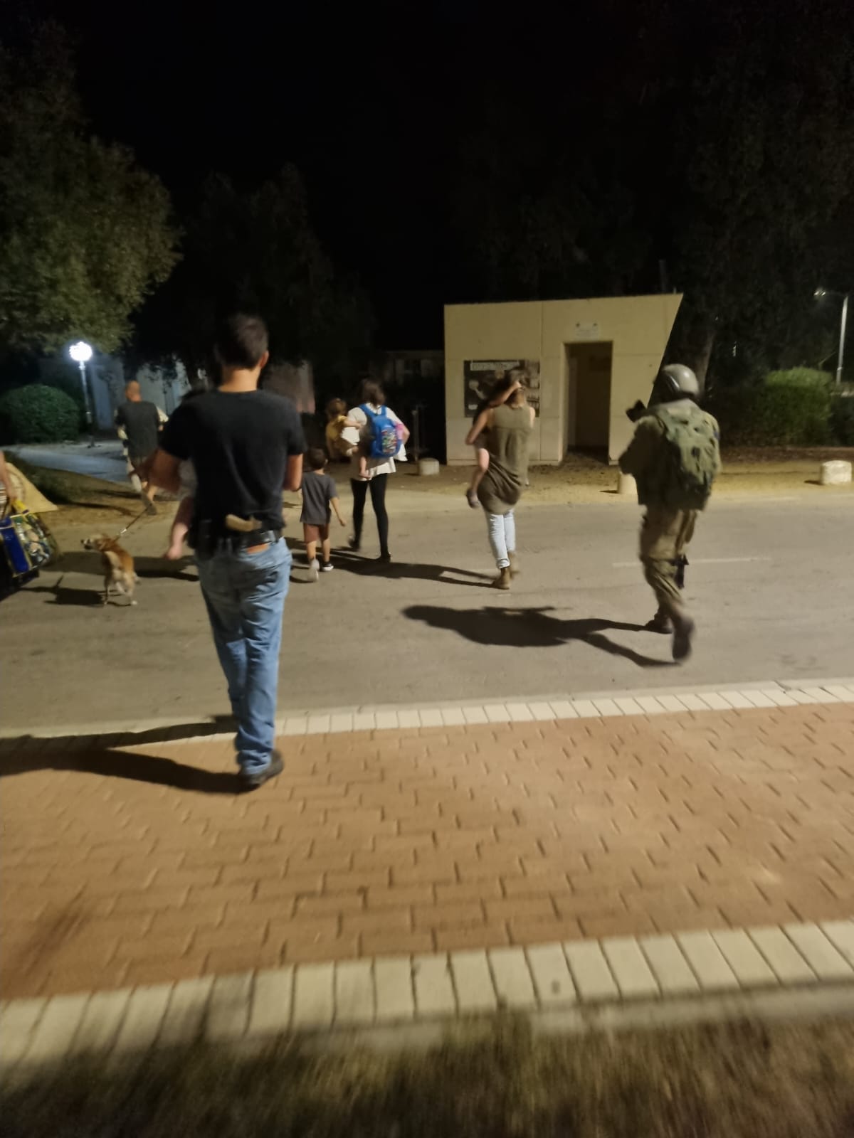 A soldier and civilians walk down a street
