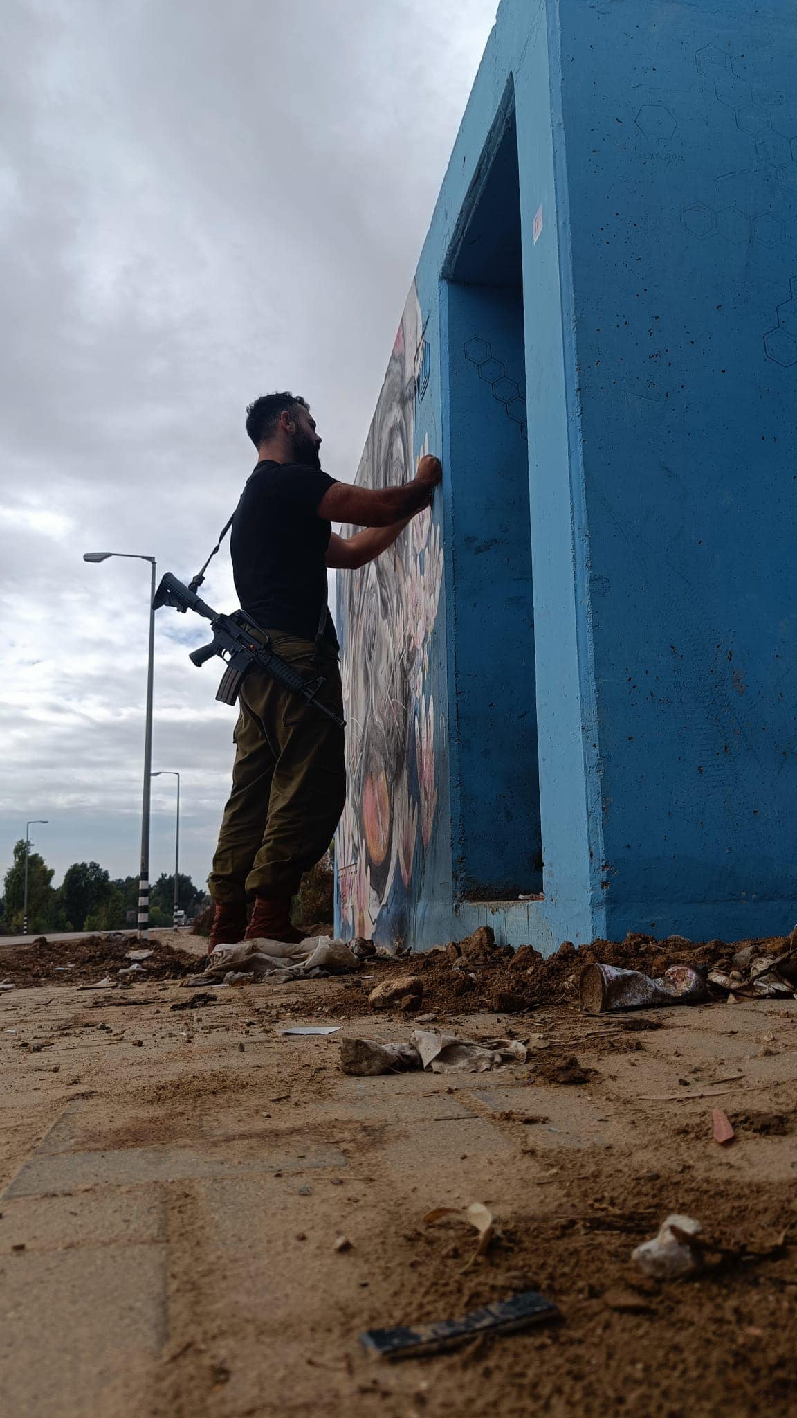 Nissim G. is standing near to a shelter with a weapon