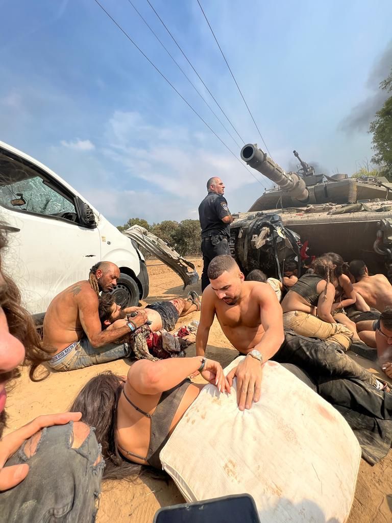People hide behind a tank and lie on the ground