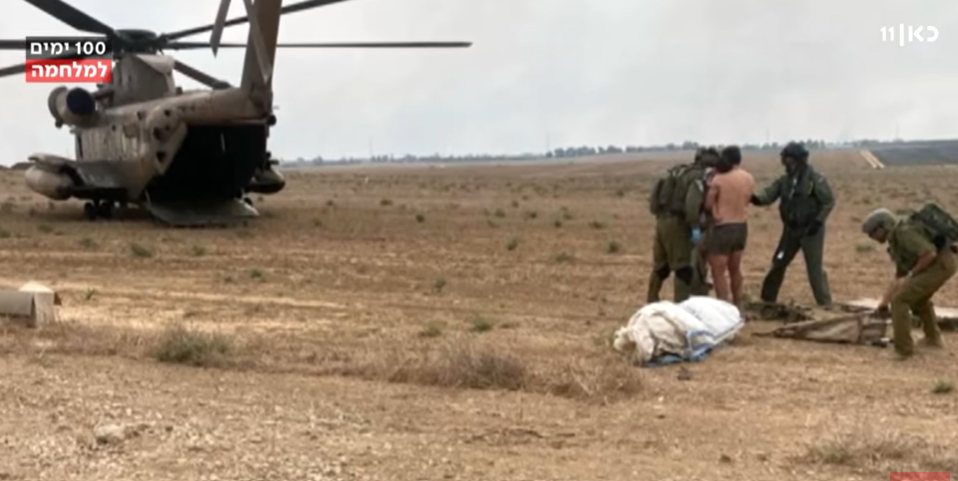 In an open area several soldiers and a military helicopter are helping someone