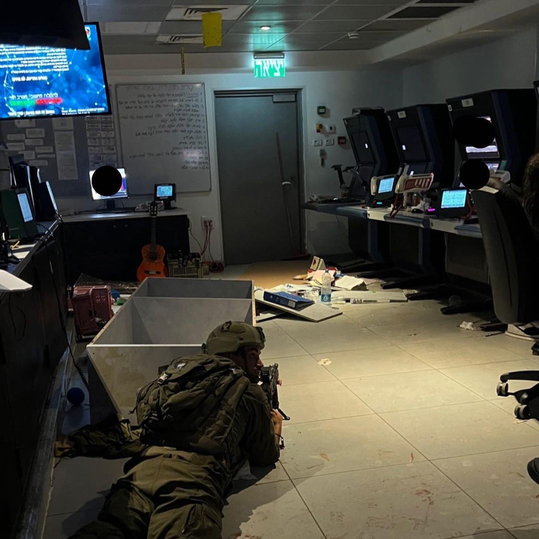 A soldier hides behind computers in a military base