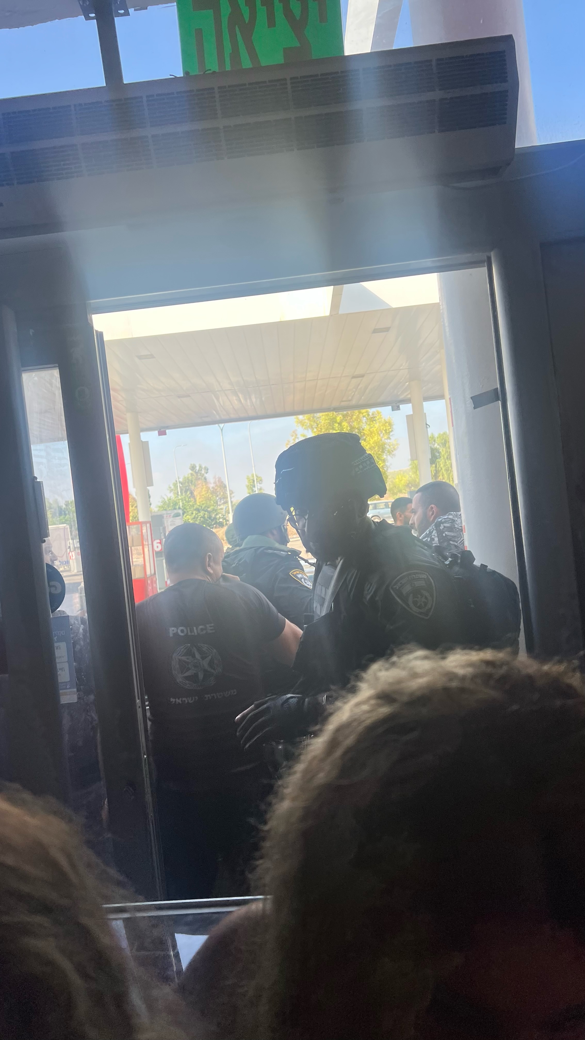 A policeman is standing at the entrance to the gas station