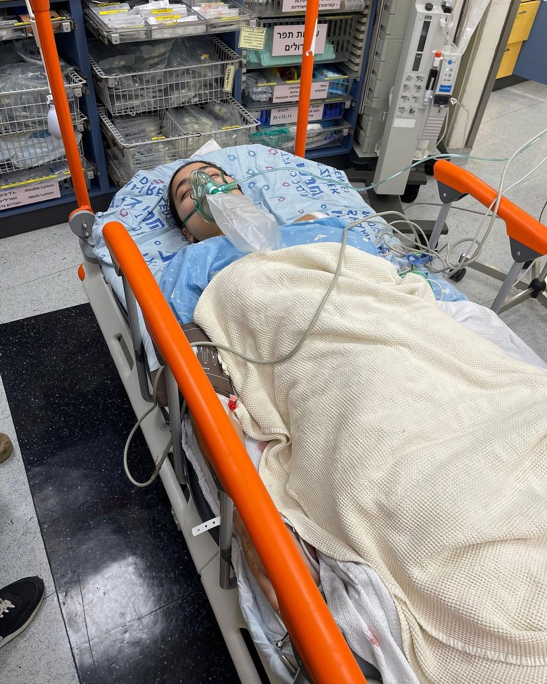 Eden R lies on a hospital bed and is being breathed by a respirator